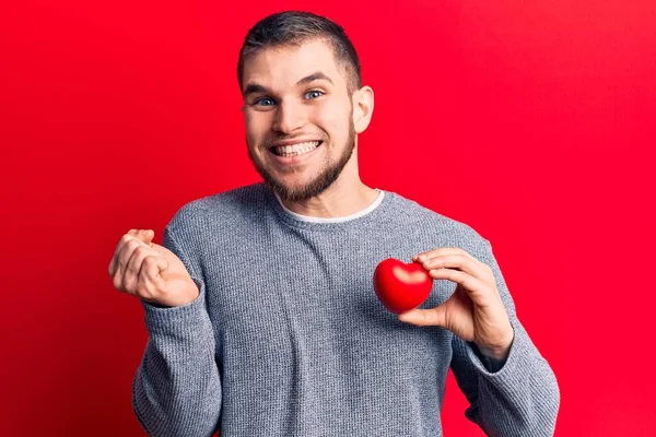 Joven Hombre Guapo Sosteniendo Corazón Gritando Orgulloso Celebrando Victoria Éxito —  Fotos de Stock