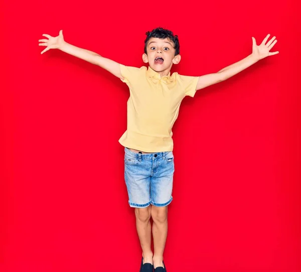 Adorabile Bambino Indossa Vestiti Casual Saltando Isolato Sfondo Rosso — Foto Stock