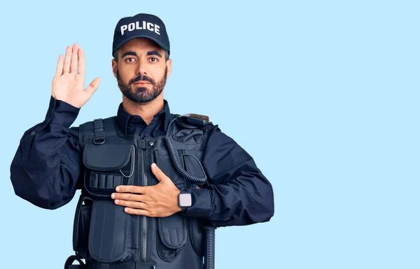 Ung Latinamerikan Man Klädd Polisuniform Svär Med Handen Bröstet Och — Stockfoto