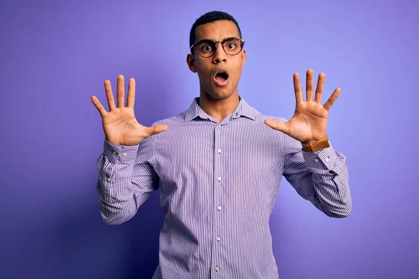 紫色の背景に縞模様のシャツと眼鏡を身に着けているハンサムなアフリカ系アメリカ人男性は 手の手のひらでジェスチャーを停止します — ストック写真