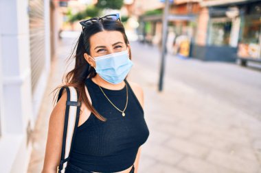 Tıbbi maske takan güzel esmer bir kadın. Şehir caddesinde yürürken
