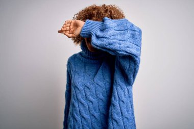 Genç ve güzel Afro-Amerikan kadın balıkçı yaka kazak giyip beyaz arka plan üzerine gözlerini kapatarak neşeli ve komik gülümsüyor. Kör kavram.