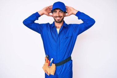 Kıvırcık saçlı ve ayı gibi giyinen yakışıklı genç adam rahatlıyor ve esniyor, kolları ve elleri başının ve boynunun arkasında mutlu gülümsüyor. 