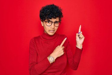 Güzel Afro-Amerikan Afro kadın balıkçı yaka kazak ve gözlük takıyor. Endişeli ve gergin bir tarafı var. Endişeli ve şaşırmış bir ifade.