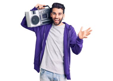 Sakallı genç yakışıklı adam klasik müzik dinleyip zaferi kutluyor. Gülümsüyor ve elleri havada bir şekilde ifade ediyor. 