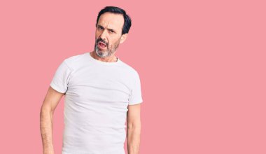 Orta yaşlı yakışıklı bir adam şok suratlı sıradan bir tişört giyiyor, şüpheci ve alaycı görünüyor, ağzı açık kalınca şaşırıyor. 