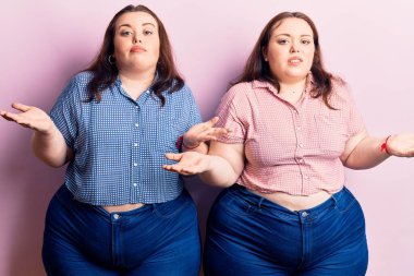 Genç ve cüsseli ikizler gündelik giysiler giyiyorlar ve kolları açık, hiçbir fikirleri yok.. 