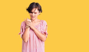 Kısa saçlı, günlük giysiler giyen, ellerinde ve parmaklarında ağrı olan, eklem iltihabı olan güzel bir genç kadın. 