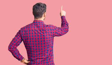 Ayılı yakışıklı genç adam, rahat bir gömlek giyip tersten öne doğru parmak eliyle poz veriyor. 