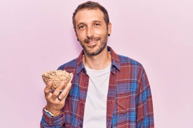 Genç yakışıklı adam mısır gevreği tutuyor. Pozitif ve mutlu görünüyor. Duruyor ve gülümsüyor. 