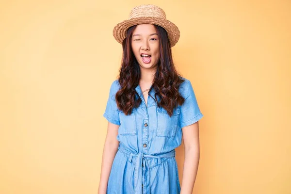 年轻美丽的中国姑娘戴着夏帽眨眼看着摄像机 脸上洋溢着性感的表情 笑容满面 — 图库照片