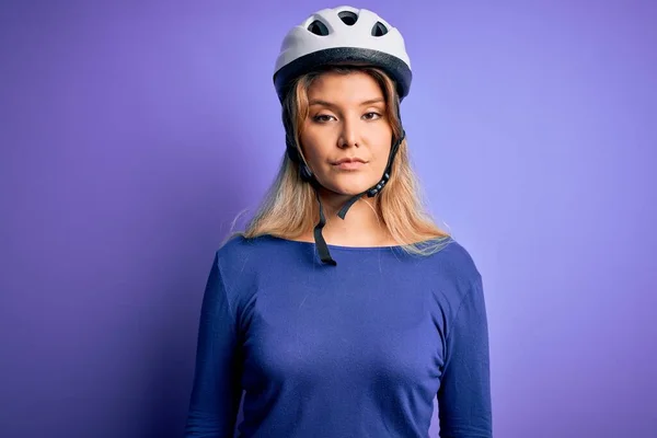 年轻美丽的金发骑车人 头戴紫色背景的自行车安全帽 脸上表情严肃 简单而自然地看着相机 — 图库照片