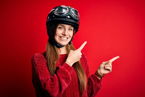 Junge Schöne Rothaarige Motorradfahrerin Mit Motorradhelm Über Rotem Hintergrund Lächelt — Stockfoto