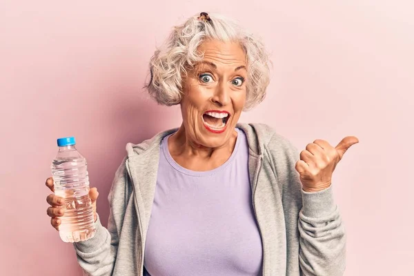 Starsza Siwowłosa Kobieta Odzieży Sportowej Pijąca Butelkę Wody Skierowanej Kciukiem — Zdjęcie stockowe