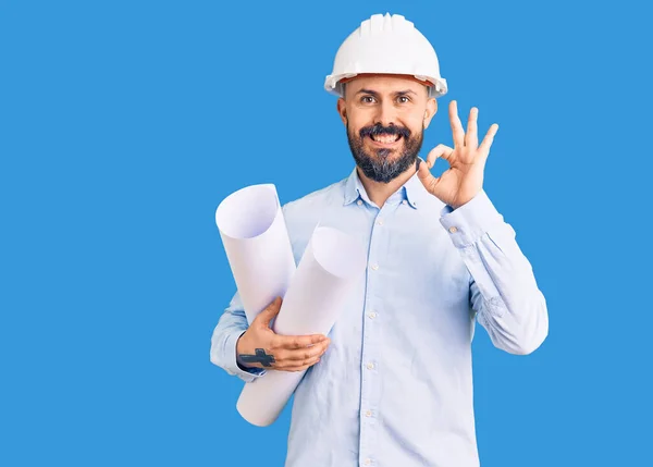 Young Handsome Man Wearing Hardhat Holding Paper Blueprints Doing Sign — Stock Photo, Image