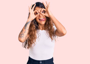 Dürbünlü dürbün gibi güzel hareketler yapan, parmaklarından içeri bakan dövmeli genç İspanyol kadın. çılgın ifade. 