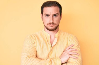 Gündelik kıyafetler giyen, kuşkucu ve gergin genç yakışıklı bir adam. Yüzünde çapraz kollarla onaylamayan bir ifade var. negatif kişi. 