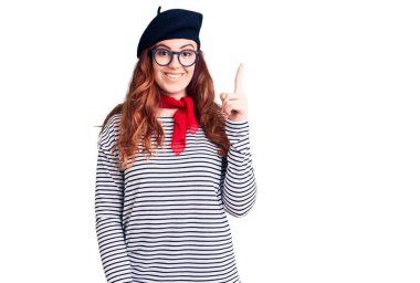Fransızca giyinen genç ve güzel bir kadın. Bere takmış, başarılı bir fikirle işaret ediyor. Heyecanlı ve mutlu. Bir numara.. 