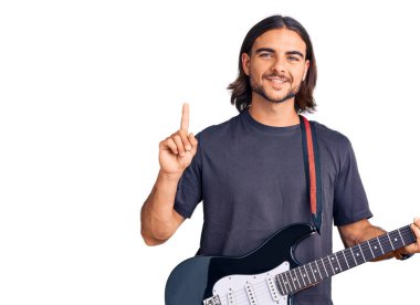 Elektro gitar çalan genç yakışıklı bir adam bir fikre ya da soru işaretine şaşırdı ve mutlu bir yüzle işaret etti. 