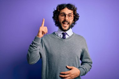 Sakallı, kravatlı ve gözlüklü, mor arka planda duran yakışıklı iş adamı başarılı bir fikri işaret ediyor. Heyecanlı ve mutlu. Bir numara..