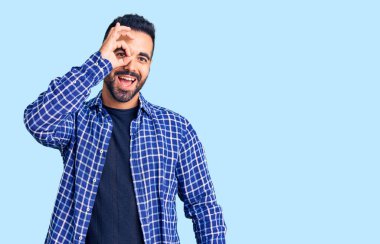 Gündelik kıyafetler giyen genç İspanyol adam el hareketleriyle gülümsüyor ve mutlu yüzüyle parmaklarından bakıyor.. 