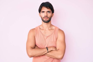 Gündelik kıyafetler giyen yakışıklı İspanyol adam şüpheci ve gergin, yüzünde çapraz kollu tasvip etmeyen ifade. negatif kişi. 