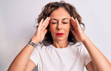 Orta yaşlı, güzel, esmer bir kadın, günlük tişört giyiyor, beyaz arka planda el üstünde duruyor, başı ağrıyor, stres yüzünden. Migren ağrısı..