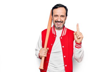 Orta yaşlı yakışıklı sporcu ceketi giyiyor beyzbol oynuyor ahşap sopayla gülüyor bir fikirle ya da soru işareti yaparak mutlu bir yüzle, bir numara