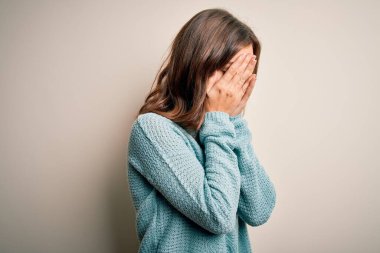 İzole edilmiş arka planda günlük mavi süveter giyen genç sarışın kız. Ağlarken suratını ellerle kapatan üzgün bir ifade. Depresyon kavramı.