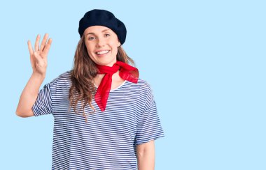 Fransız beresi ve çizgili tişört giyen genç ve güzel sarışın kadın dört numaralı parmaklarını gösterip gösterirken kendinden emin ve mutlu gülümsüyor.. 