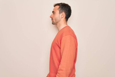 Mavi gözlü, sıradan bir süveter giyen, beyaz arka planda durup yan yan yan bakan, rahat bir poz veren, kendine güvenen bir gülümsemesi olan genç yakışıklı bir adam..