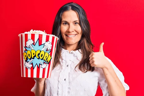 Mladá Krásná Brunetka Žena Jíst Balíček Popcornů Izolovaném Červeném Pozadí — Stock fotografie