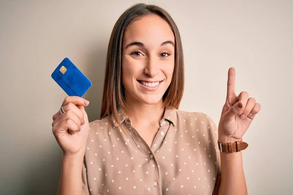 Młoda Piękna Klientka Trzymająca Kartę Kredytową Zapłaty Białe Tło Zaskoczona — Zdjęcie stockowe