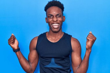 Genç Afrikalı Amerikalı erkek spor giyer gururla bağırır, zaferi kutlar ve kollarını kaldırarak heyecanlanır. 