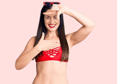 Bikini giyen, gülümseyen, elleri ve parmakları gülen genç, beyaz bir kadın. yaratıcılık ve fotoğrafçılık kavramı. 