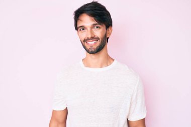 Yakışıklı, beyaz tişört giyen, pozitif ve mutlu görünen, kendine güvenen, gülümseyen, dişlerini gösteren yakışıklı bir İspanyol. 