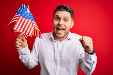 Mavi gözlü genç adam, kırmızı izole edilmiş arka planda Amerika Birleşik Devletleri bayrağını tutuyor. Gururla bağırıyor, zaferi ve başarıyı kutluyor. Çok heyecanlı, coşkulu bir duygu.