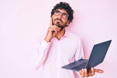 Kıvırcık saçlı ve ayılı yakışıklı bir adam bilgisayar bilgisayarı kullanıyor ciddi bir yüz ifadesi takınıyor eli çenesinde soruyu düşünüyor, kafa karıştırıcı bir fikir. 