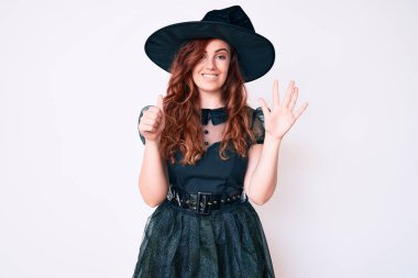 Cadı cadılar bayramı kostümü giymiş genç ve güzel bir kadın. Altıncı parmaklarını gösterip gülümserken kendinden emin ve mutlu.. 