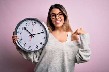 Genç, güzel, esmer, gözlüklü bir kadın geri sayım yapıyor. Büyük saati kullanarak kendini işaret ediyor.