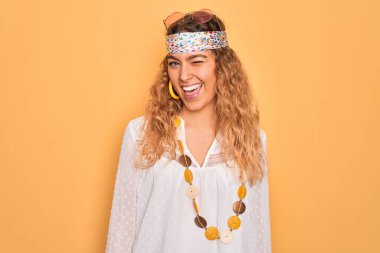 Mavi gözlü, güneş gözlüğü takan ve aksesuar takan genç, güzel sarışın hippi kadın kameraya seksi bir ifadeyle bakıyor, neşeli ve mutlu bir yüzle..