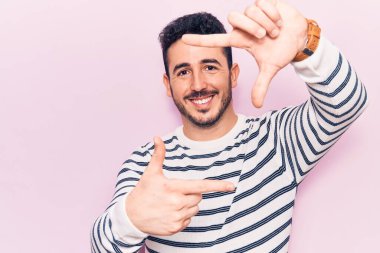 Gündelik kıyafetler giyen, gülümseyen, elleri ve parmakları gülen yüzlü, çerçeveli bir İspanyol. yaratıcılık ve fotoğrafçılık kavramı. 