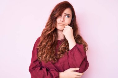 Kış süveteri giyen genç ve güzel bir kadın ciddi bir yüz ifadesi, eli çenesinde soru soran, kafa karıştırıcı bir fikir hakkında düşünceli. 