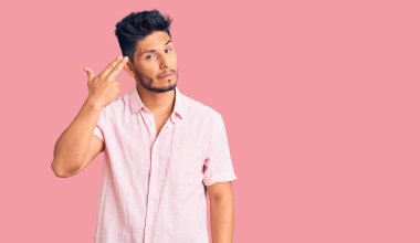 Yakışıklı Latin Amerikalı genç adam, sıradan bir yaz tişörtü giyip kendini vuruyor ve kendini ve parmaklarını silah gibi kullanıyor. İntihar jesti.. 