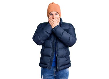 Kışlık kıyafet giyen genç yakışıklı adam yanlışlıkla ağzını ellerinle kapatarak şok oldu. gizli kavram. 