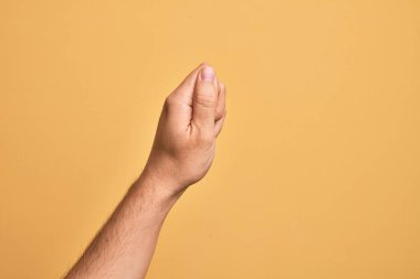İzole edilmiş sarı arka planda parmaklarını gösteren beyaz bir adamın eli. Parmak, iş ve reklamla boş bir alan tutuyor.