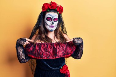 Ölü kostümü giymiş genç bir kadın sarıya bürünmüş, kendine güvenen, yüzünde gülümseme, kendini gururlu ve mutlu olarak gösteren bir kadın.. 