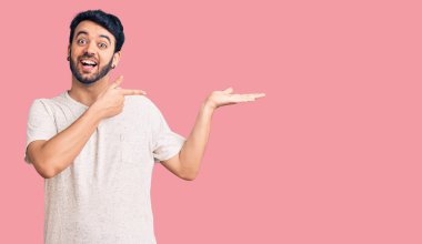 Gündelik kıyafetler giyen genç İspanyol adam kameraya hayret ediyor ve gülümsüyor.. 