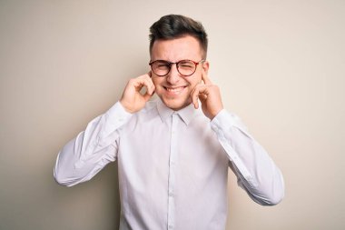 Gözlük takan yakışıklı iş adamları ve izole edilmiş arka planda zarif gömlekler. Yüksek sesli müzik sesi için kulakları parmaklarıyla kapatıyor. Sağır kavramı.