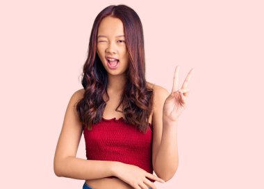 Genç, güzel, sıradan kıyafetler giyen, gülümseyen, kameraya göz kırpan, zafer işareti yapan Çinli bir kız. İki numara.. 